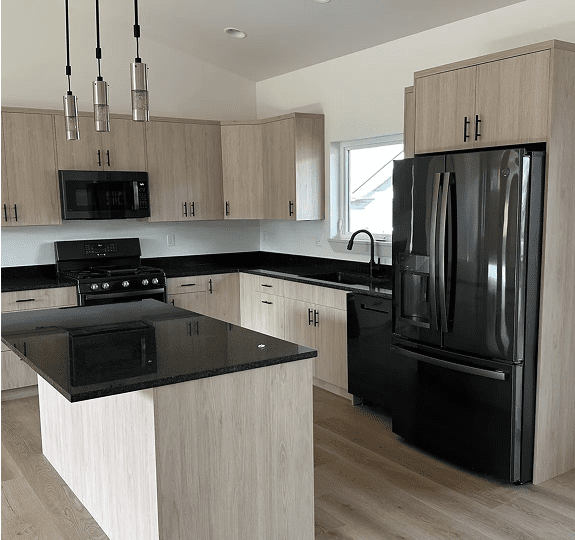 Modern kitchen with black appliances and light wood cabinetry.