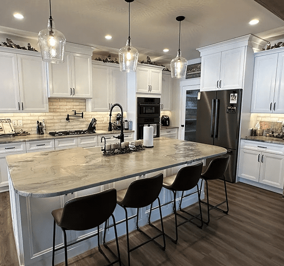 Modern kitchen with marble island, black chairs, and stainless steel appliances.